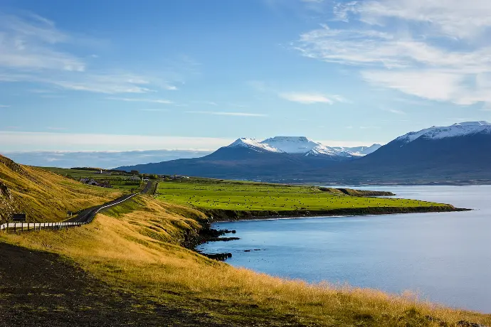 field and mountain near body of water